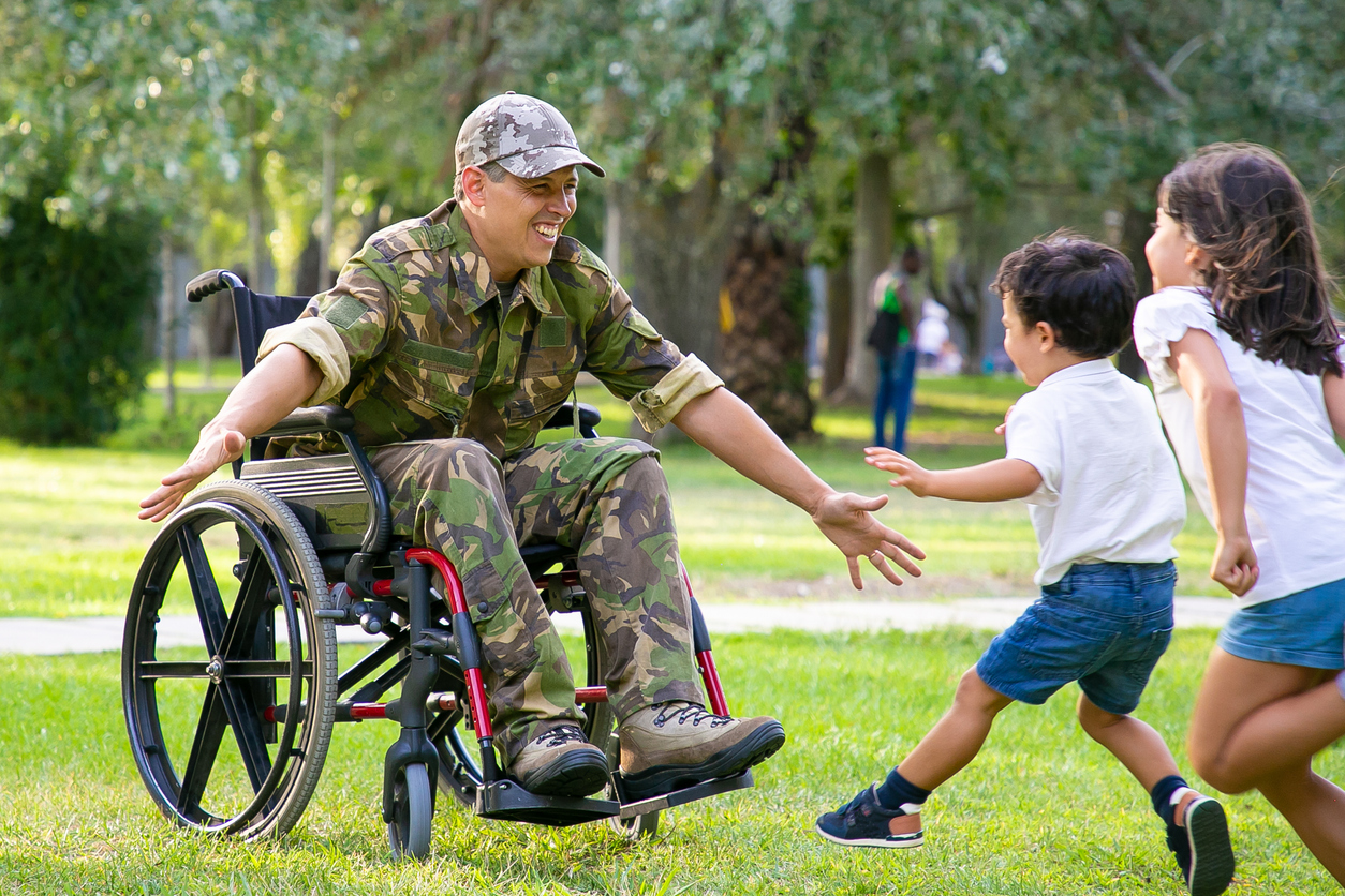 Cheerful kids meeting disabled military dad and running to disabled man in camouflage with open arms for hug.